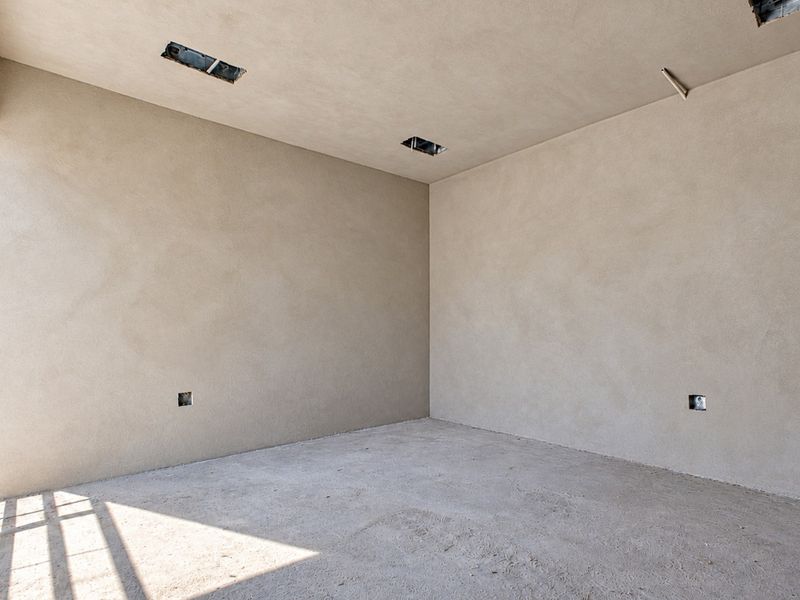 An unfinished interior room featuring raw plastered walls, concrete flooring, and exposed electrical points, offering a blank canvas for custom interior finishes.