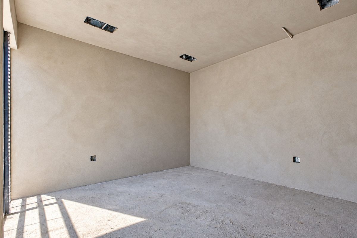 An unfinished interior room featuring raw plastered walls, concrete flooring, and exposed electrical points, offering a blank canvas for custom interior finishes.