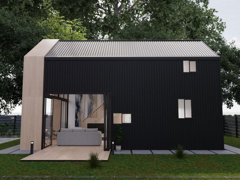 Modern rear exterior view of a townhouse featuring black metal cladding, timber accents, a private deck, and large sliding glass doors.