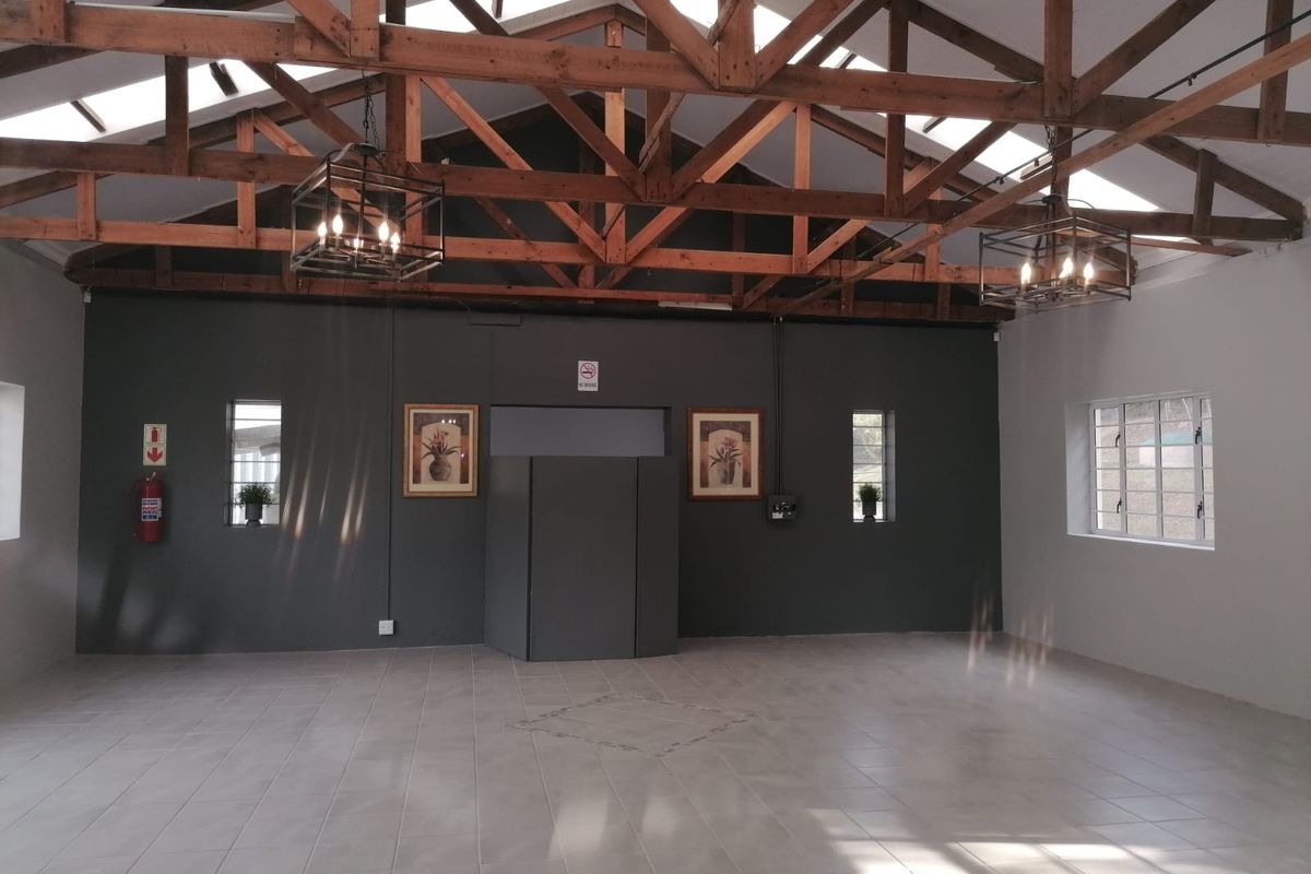 Spacious open-plan restaurant area featuring high exposed timber roof trusses, tiled flooring, and natural light from skylights and windows.