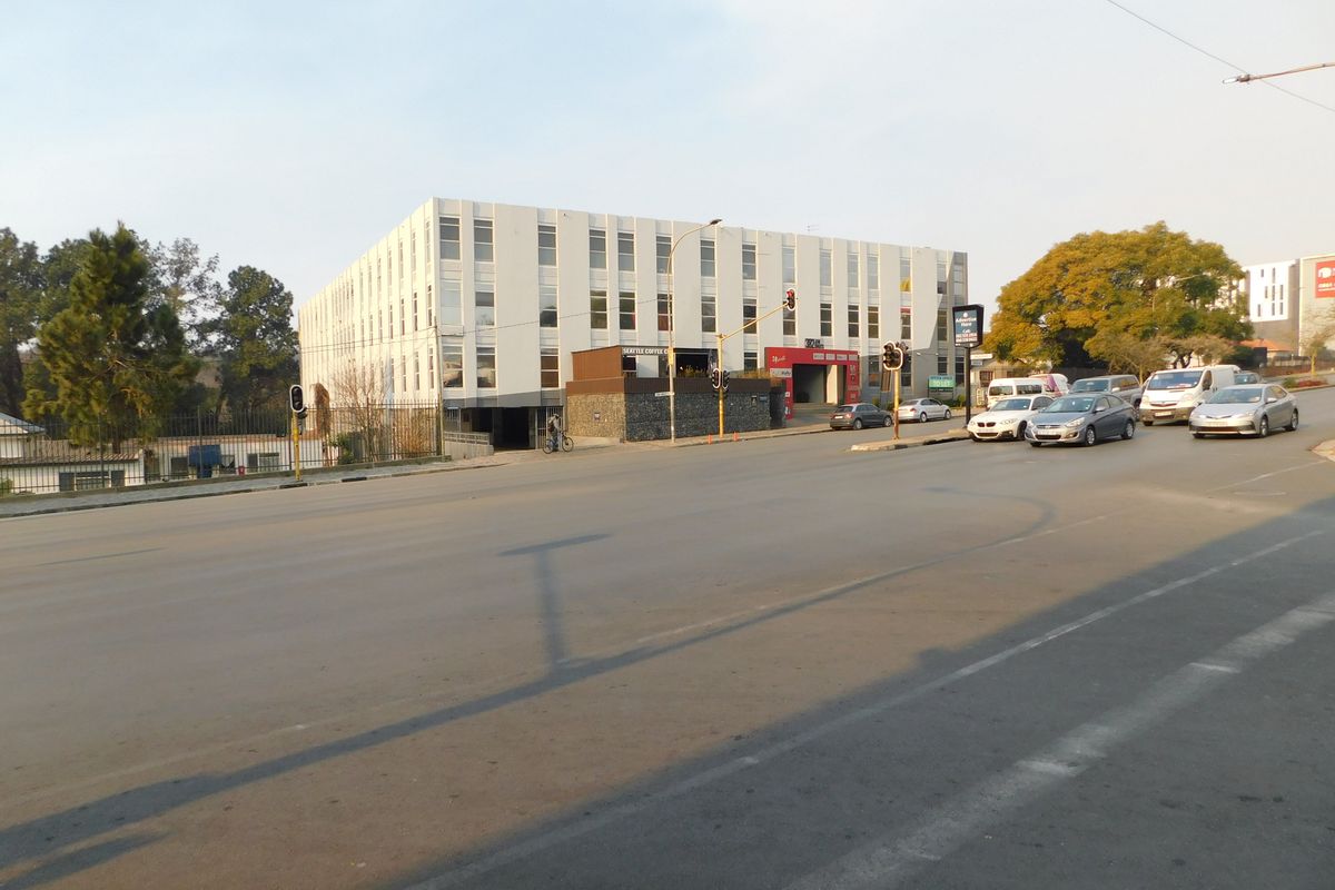 Street-level view of a multi-story commercial office building with a prominent facade and surrounding road infrastructure.