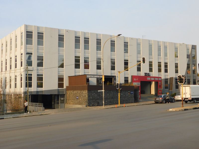 A multi-story commercial office building featuring a modern facade with large windows, stone-clad base, and a prominent street-level entrance.
