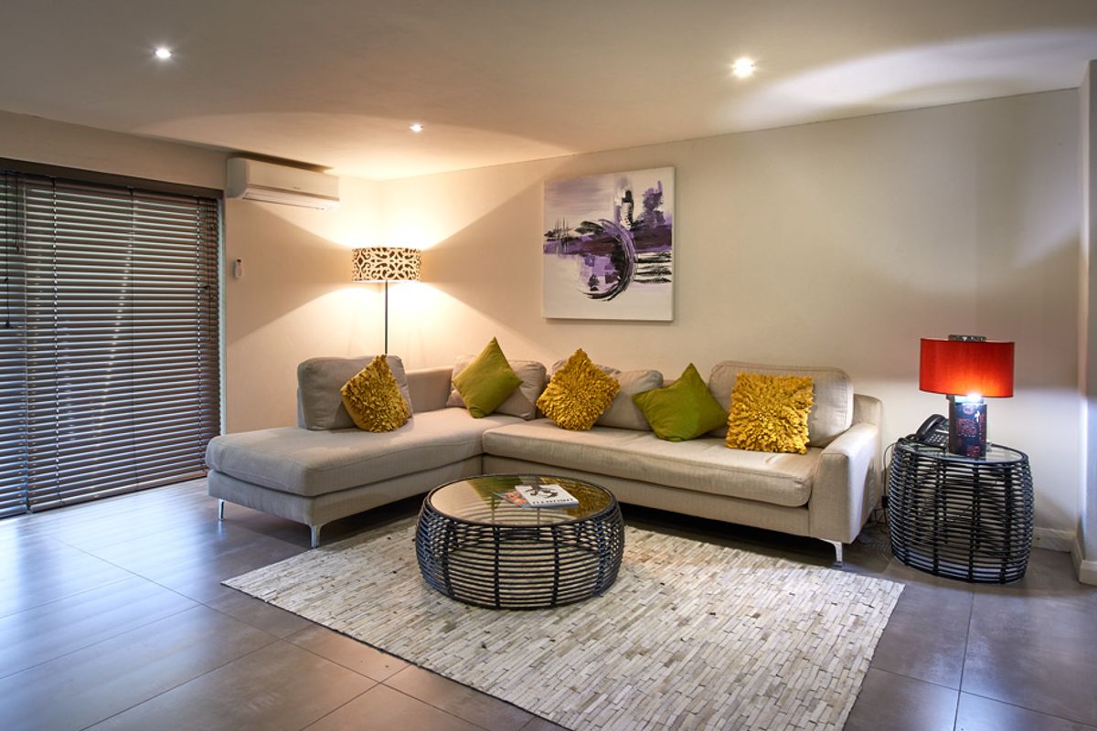 A comfortable living room featuring tiled flooring, recessed ceiling lighting, and a wall-mounted air conditioning unit, with sliding door access to the exterior.
