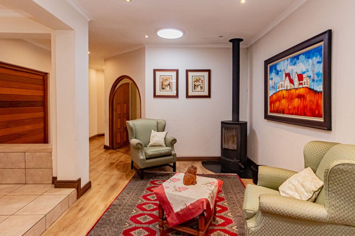 A cozy living room featuring a modern black wood-burning fireplace, recessed ceiling lighting, a skylight, and elegant arched doorways.