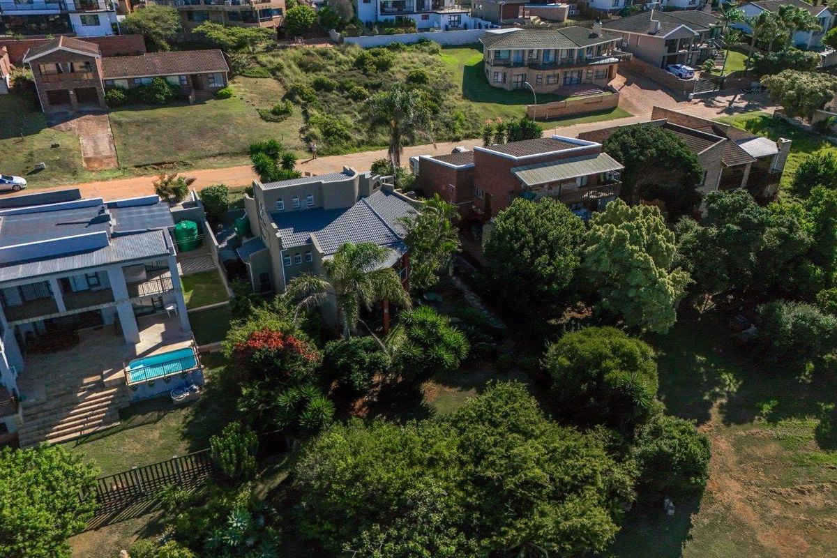 Aerial view of the property showcasing the residential building, surrounding landscaped garden, and established trees within a suburban estate setting.