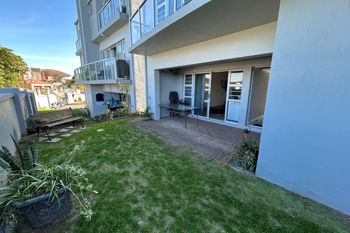 A ground floor apartment featuring a private paved patio area and a small garden, accessible via sliding glass doors from the living space.