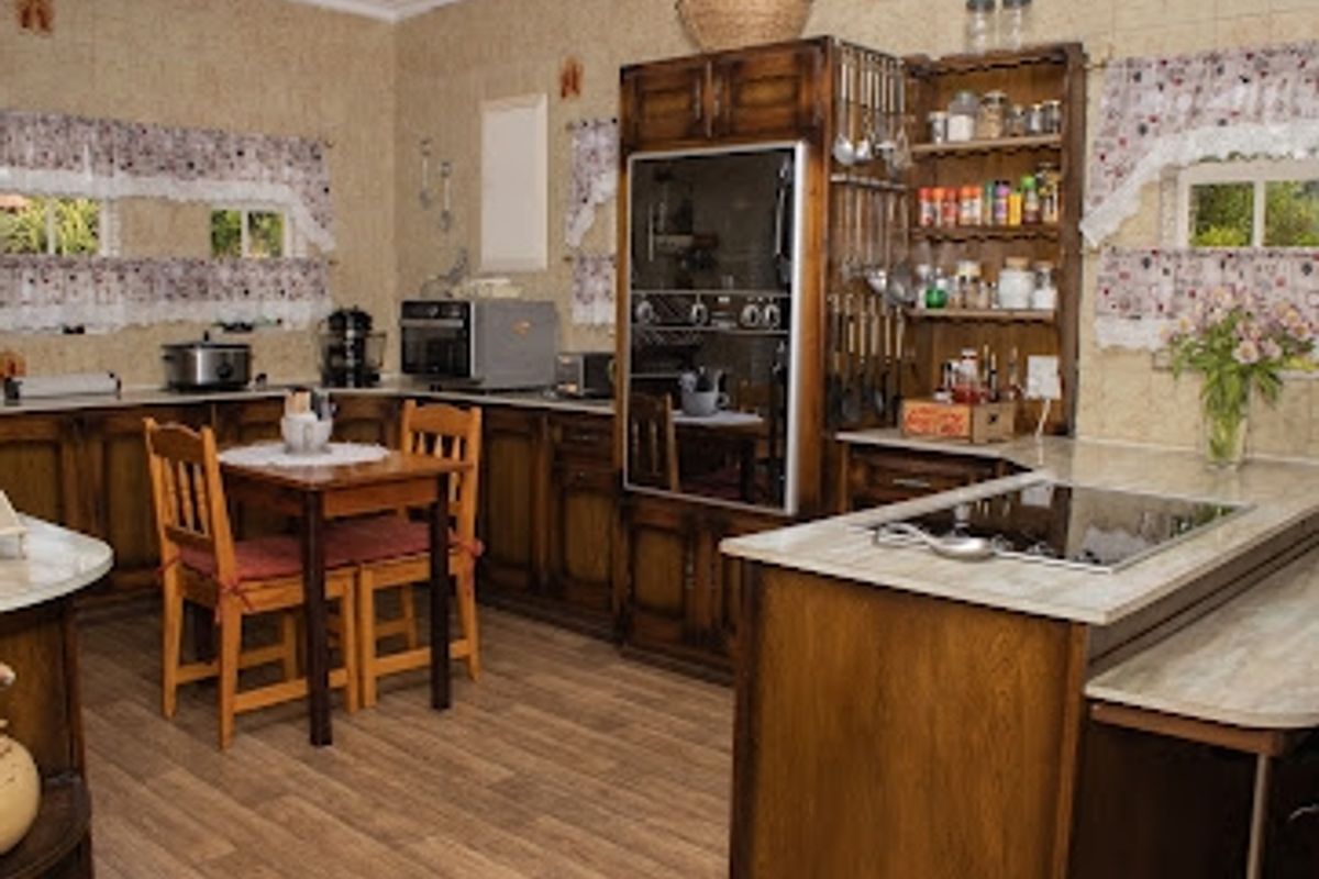 A traditional kitchen featuring extensive wooden cabinetry, built-in oven, electric hob, and laminate flooring, offering a functional layout with ample storage space.