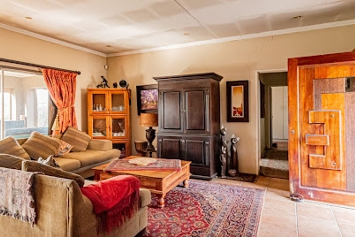 A cozy living room featuring tiled flooring, recessed lighting, and a distinctive solid wood front door, with direct access to an outdoor patio area.