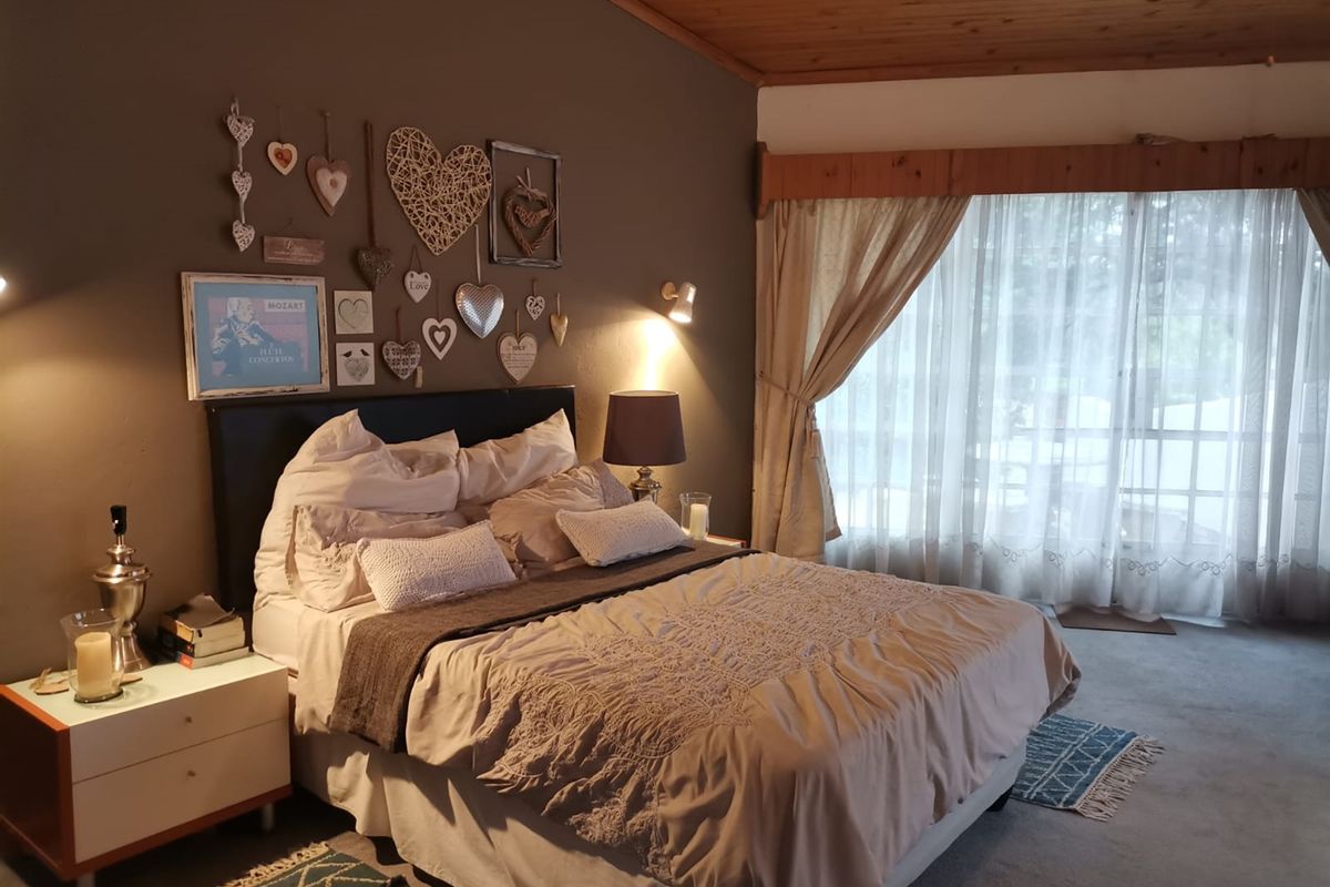 A cozy bedroom featuring a timber-paneled ceiling and large sliding glass doors that provide natural light and access to the outdoors.