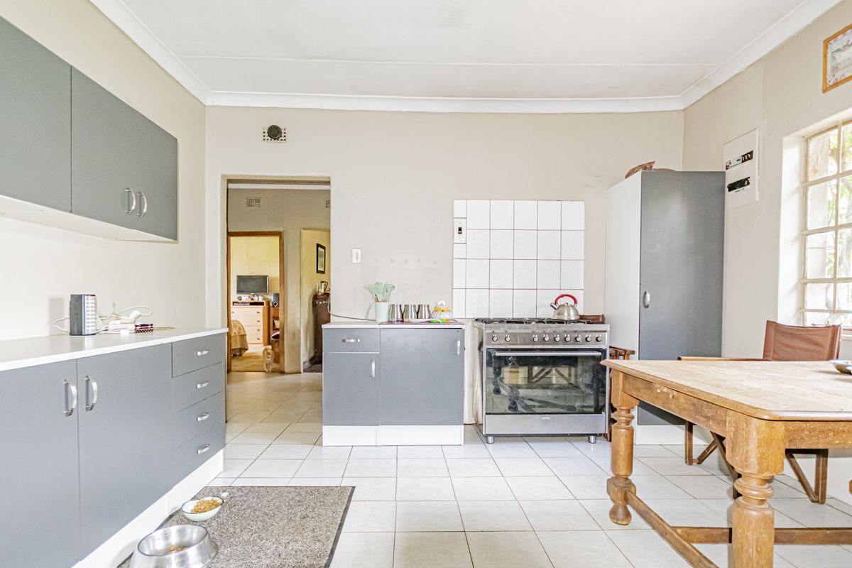 Functional kitchen featuring grey built-in cabinetry, a gas stove with oven, tiled splashback, and tiled flooring, offering a practical layout for daily use.