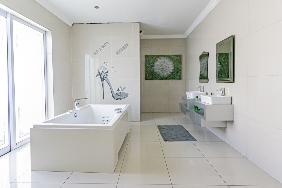 Spacious modern bathroom featuring a built-in bathtub, double wall-mounted vanity basins, and large sliding glass doors providing ample natural light.