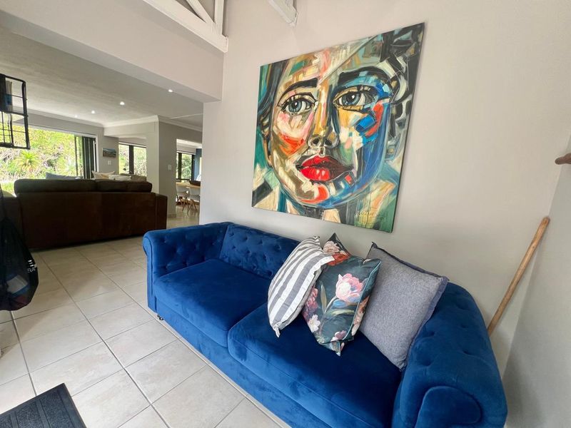 A bright living area featuring neutral tiled flooring, exposed ceiling beams, and recessed lighting, creating an open and inviting atmosphere.