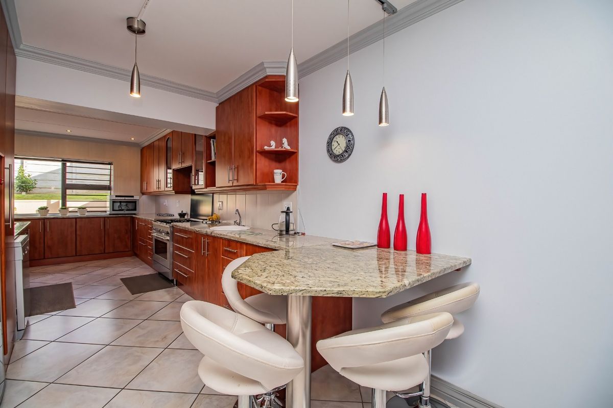 A well-maintained kitchen featuring cherry wood cabinetry, granite countertops, a breakfast bar, and tiled flooring, offering a functional and classic cooking space.