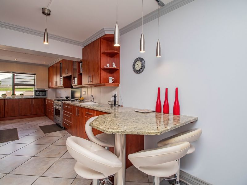 A well-maintained kitchen featuring cherry wood cabinetry, granite countertops, a breakfast bar, and tiled flooring, offering a functional and classic cooking space.
