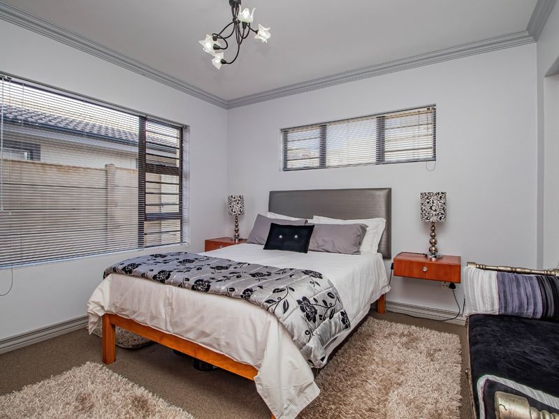A well-maintained bedroom featuring crown molding, neutral carpeting, and multiple windows fitted with horizontal blinds for natural light control.
