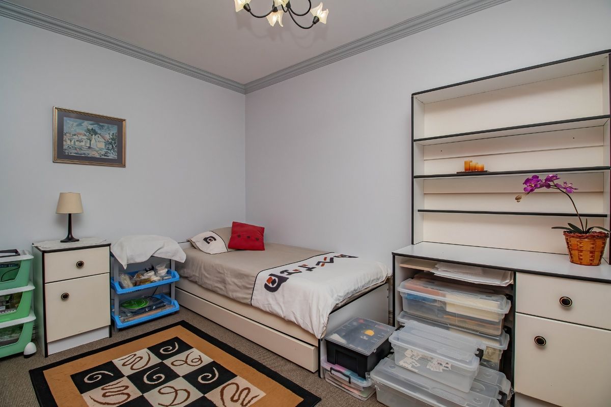 A bedroom featuring neutral walls, crown molding, and a built-in shelving unit, offering a functional space with potential for modern updates.