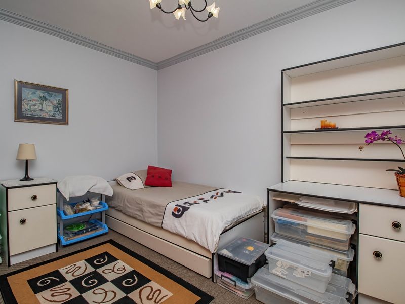A bedroom featuring neutral walls, crown molding, and a built-in shelving unit, offering a functional space with potential for modern updates.