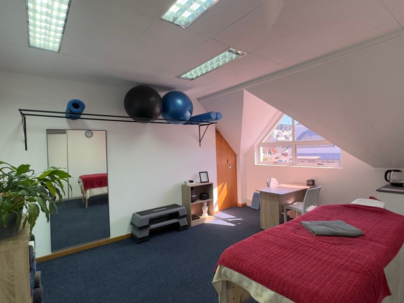A functional therapy or gym space featuring built-in cabinetry, recessed lighting, and a large window providing natural light.
