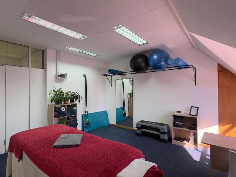 A functional gym space featuring recessed fluorescent lighting, wall-mounted storage, and a large mirror, suitable for fitness or wellness activities.