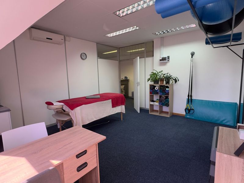 A functional therapy or fitness studio featuring carpeted flooring, recessed lighting, a wall-mounted suspension system, and a split-system air conditioning unit.