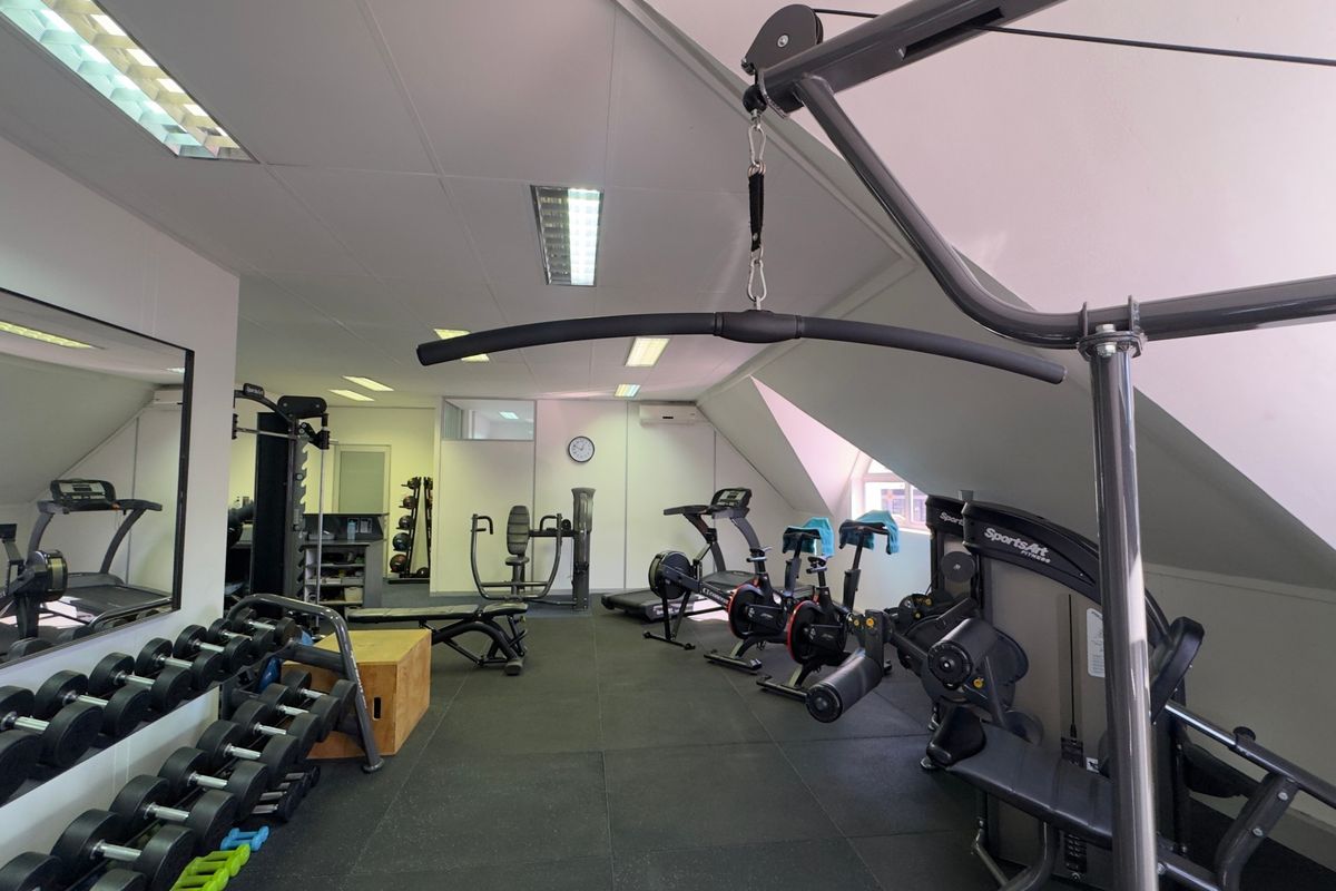 A well-equipped gym featuring rubberized flooring, recessed lighting, and wall-mounted mirrors, providing a functional space for fitness activities.