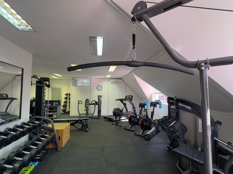 A well-equipped gym featuring rubberized flooring, recessed lighting, and wall-mounted mirrors, providing a functional space for fitness activities.