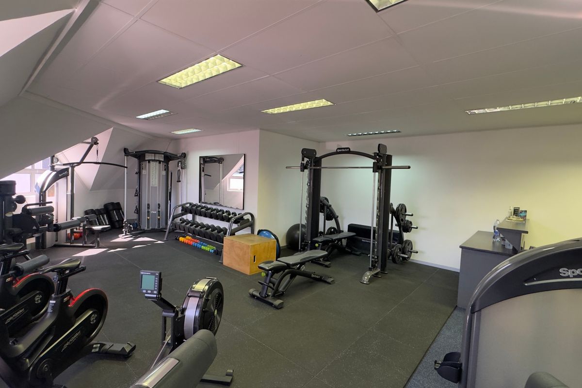 A well-equipped commercial gym space featuring rubberized flooring, recessed lighting, and a variety of professional-grade fitness equipment.