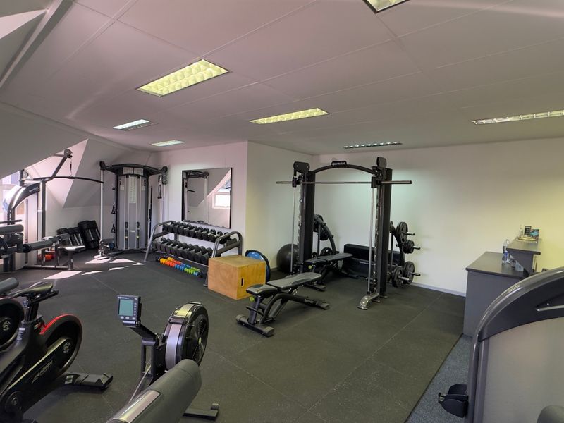 A well-equipped commercial gym space featuring rubberized flooring, recessed lighting, and a variety of professional-grade fitness equipment.