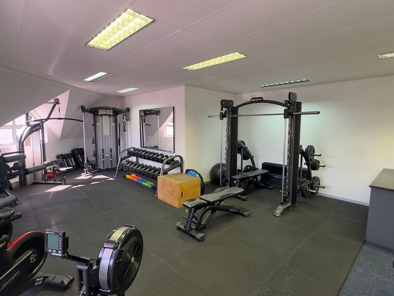 A well-equipped commercial gym space featuring durable rubber flooring, recessed lighting, and a built-in reception counter.