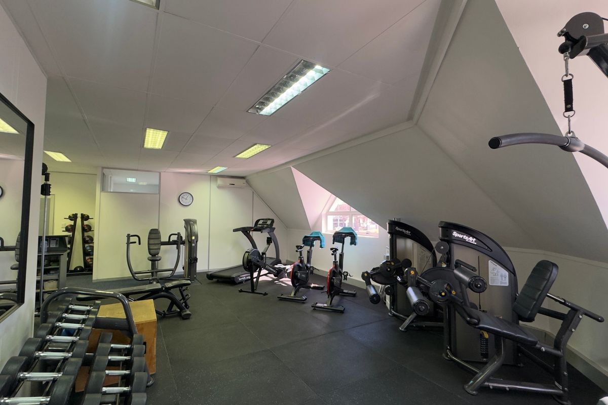 A well-maintained gym facility featuring rubberized flooring, recessed lighting, and a sloped ceiling with integrated air conditioning.