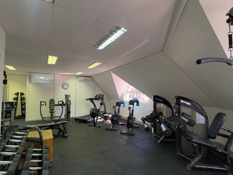 A well-maintained gym facility featuring rubberized flooring, recessed lighting, and a sloped ceiling with integrated air conditioning.