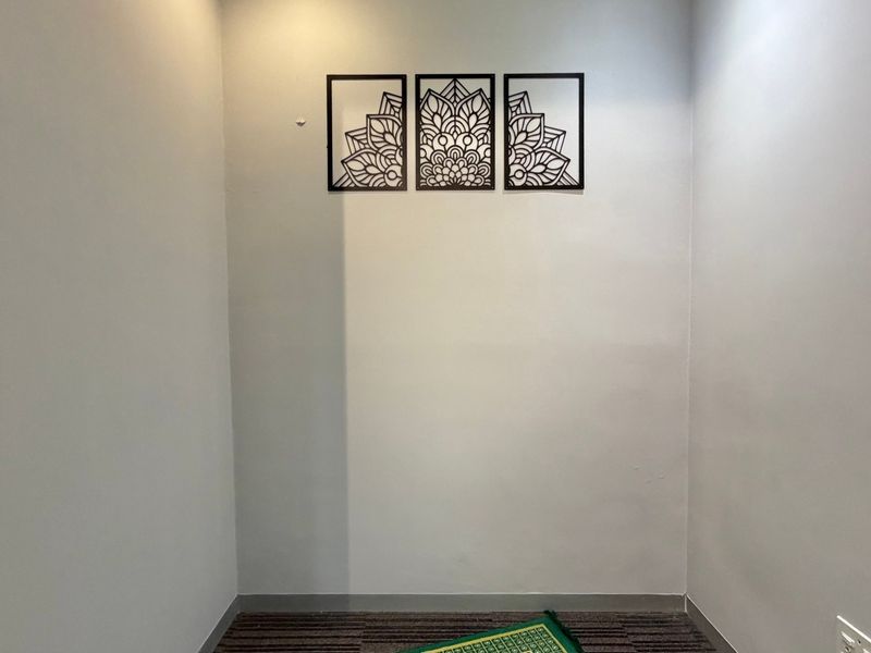 A small, neutral office space featuring carpeted flooring and a clean, minimalist aesthetic suitable for a professional workspace.