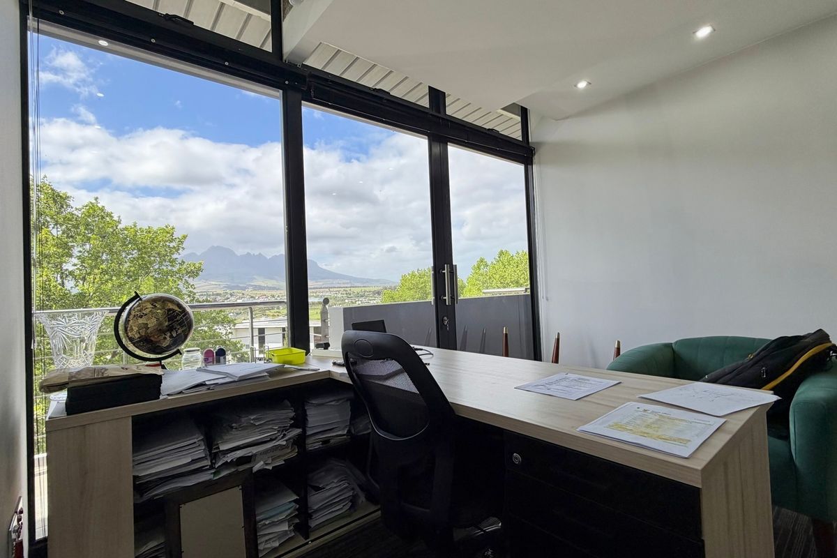 Bright office space featuring expansive floor-to-ceiling windows with scenic mountain views and direct access to a private balcony.