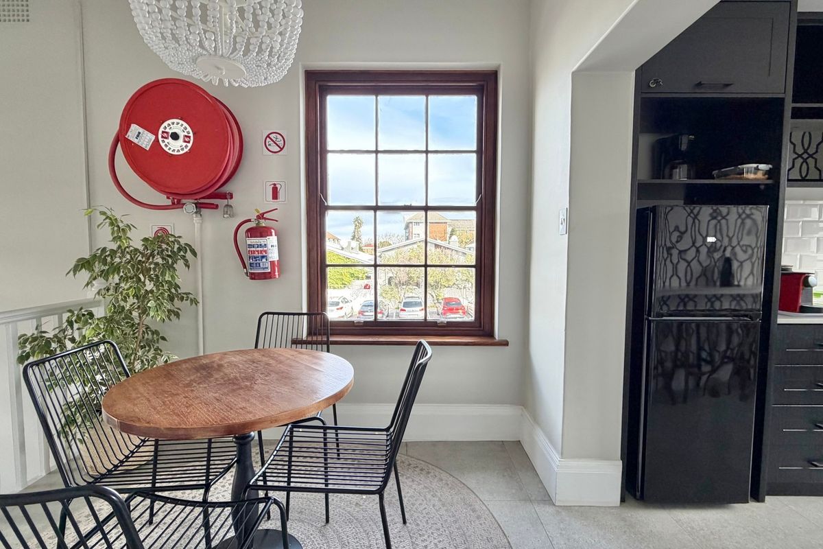 A bright kitchen area featuring a timber-framed window, subway tile backsplash, and integrated cabinetry, equipped with essential fire safety fixtures.