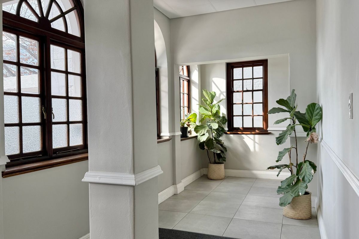 Bright and airy office space featuring classic arched timber-framed windows, neutral tiled flooring, and elegant chair rail molding throughout.
