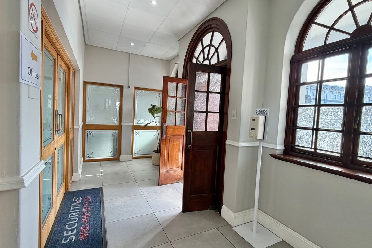 A bright and welcoming office entrance featuring tiled flooring, classic arched timber-framed windows, and elegant timber-framed glass doors.