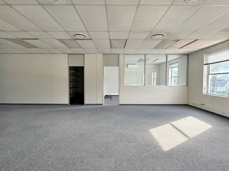 Spacious open-plan office area featuring a suspended ceiling, recessed lighting, air conditioning, and glass partitioning, providing a versatile workspace.