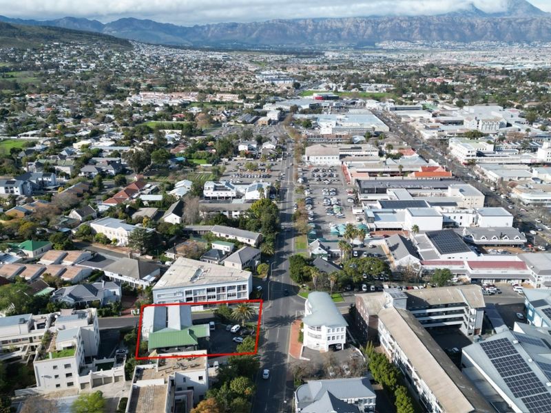 Aerial view of the office property highlighting its location within the commercial district, featuring on-site parking and proximity to local amenities.