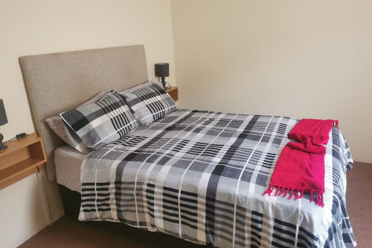 A simple bedroom featuring built-in bedside tables and neutral wall finishes.