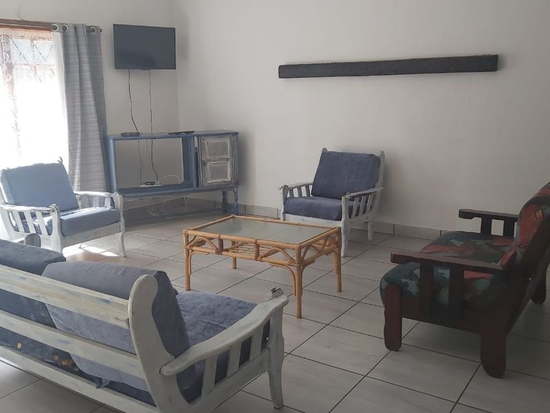 A simple living room area featuring tiled flooring and a sliding door providing access to the exterior.