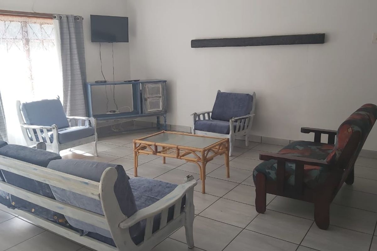 A simple living room area featuring tiled flooring and a sliding door providing access to the exterior.