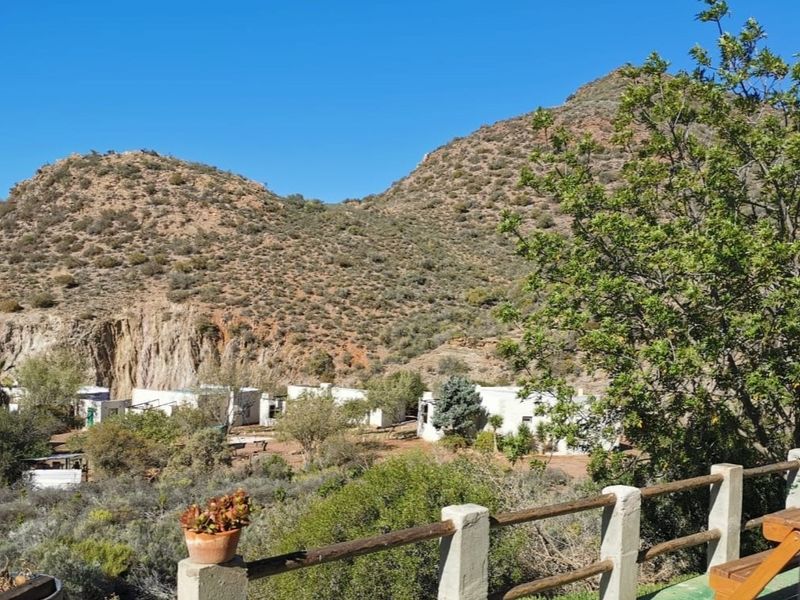 Scenic landscape view overlooking the farm property, featuring rugged mountain terrain and established vegetation with a rustic timber and concrete balustrade in the foreground.