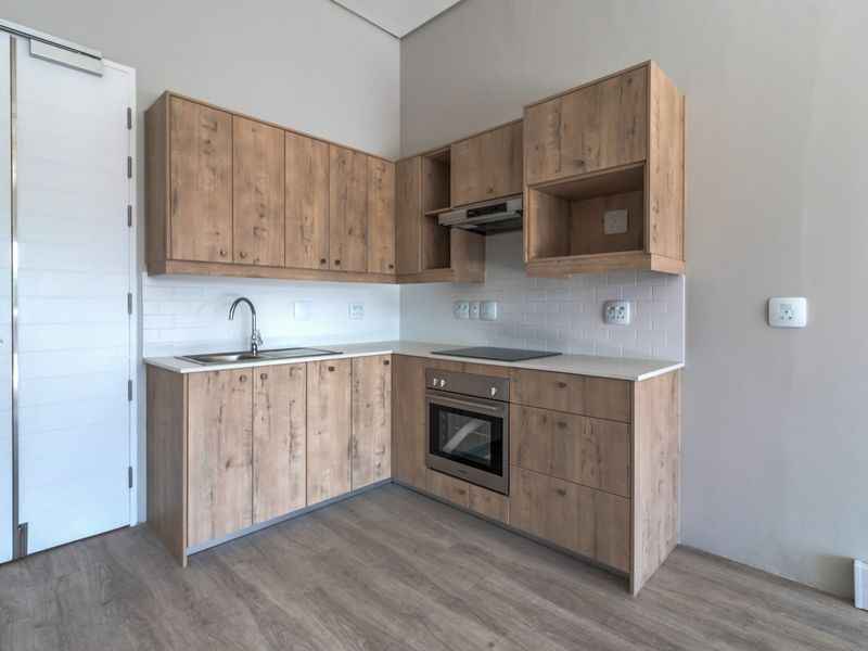 Modern kitchen featuring light wood-look cabinetry, white subway tile backsplash, stone countertops, and integrated stainless steel appliances in a clean, contemporary finish.