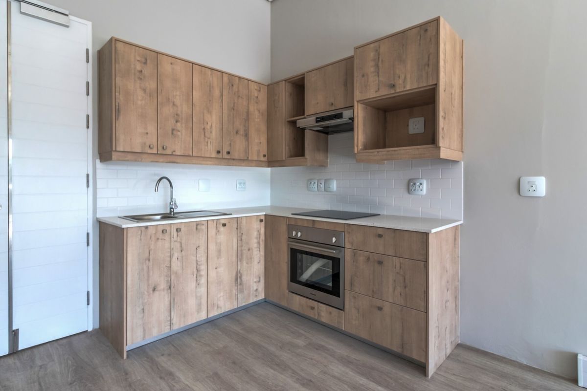 Modern kitchen featuring light wood-look cabinetry, white subway tile backsplash, stone countertops, and integrated stainless steel appliances in a clean, contemporary finish.