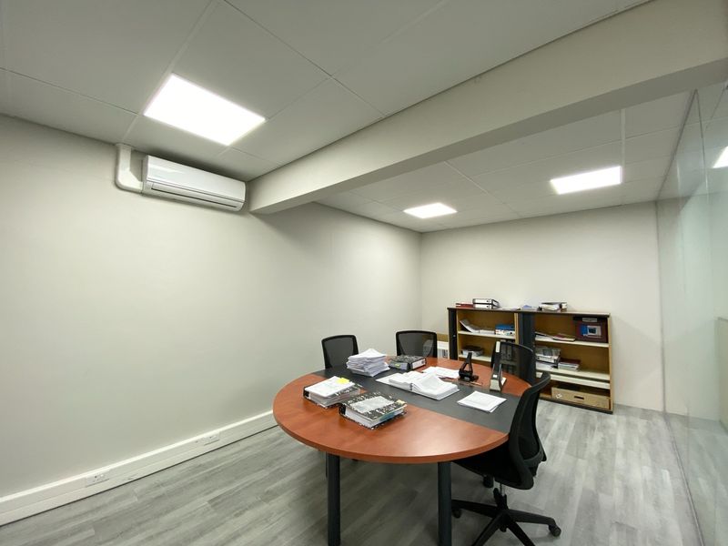 A professional office space featuring a suspended ceiling with recessed LED lighting, split-system air conditioning, and modern laminate flooring with a glass partition wall.