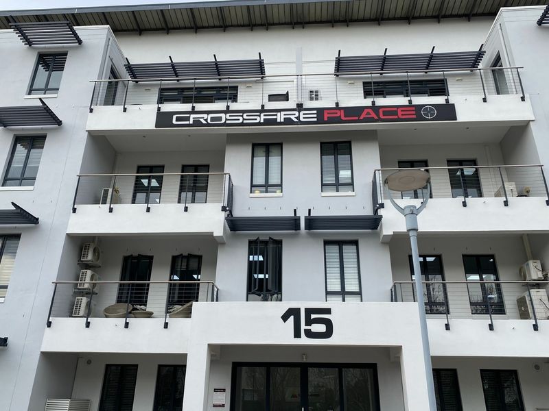 Front elevation of Crossfire Place, a modern multi-story office building featuring balconies, metal railings, and external air conditioning units.