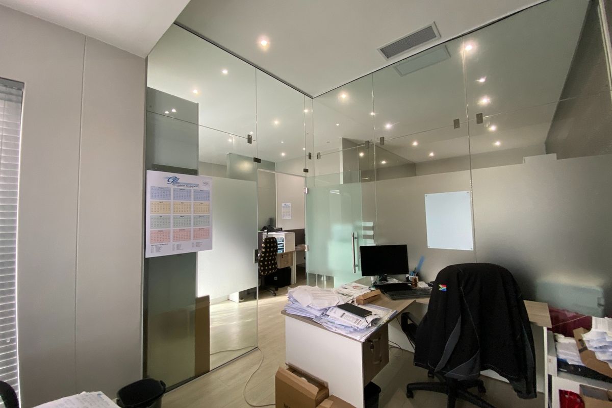 Modern office space featuring contemporary glass partition walls, recessed lighting, and integrated air conditioning, providing a professional and bright work environment.