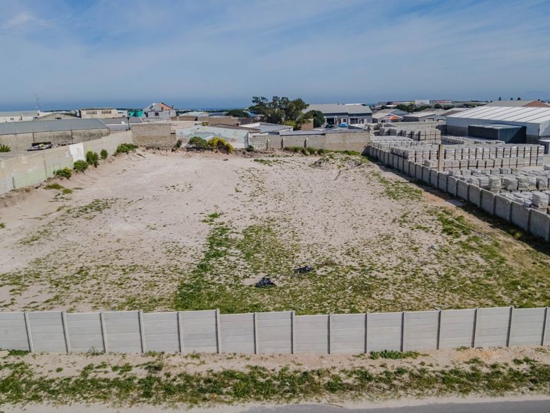 Aerial view of a vacant commercial land plot enclosed by perimeter concrete walls, situated in an industrial area.