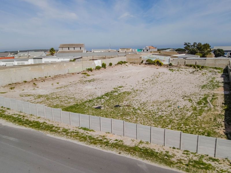 Aerial view of a vacant commercial land plot featuring perimeter walling and direct road access in an established industrial area.