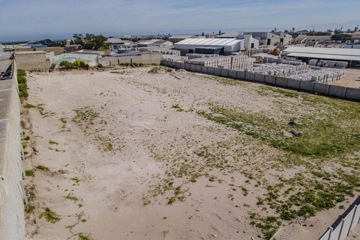 An aerial view of a vacant commercial land plot featuring perimeter boundary walls and a sandy, undeveloped surface in an industrial area.